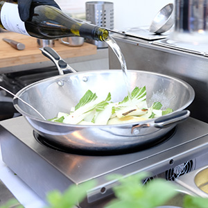 Wokpfanne wird mit Wein abgelöscht - Partyservice Schneebesen Wokpfanne wird mit Wein abgelöscht - Partyservice Schneebesen